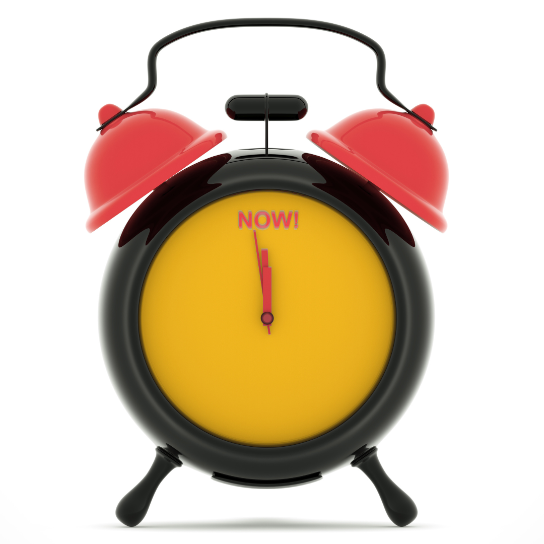 Photo of an old fashioned alarm clock. The face is yellow, the bells and arms are dark orange. Both arms are pointed at where the 12 would usually be. Instead of the 12, the word NOW! in dark orange.